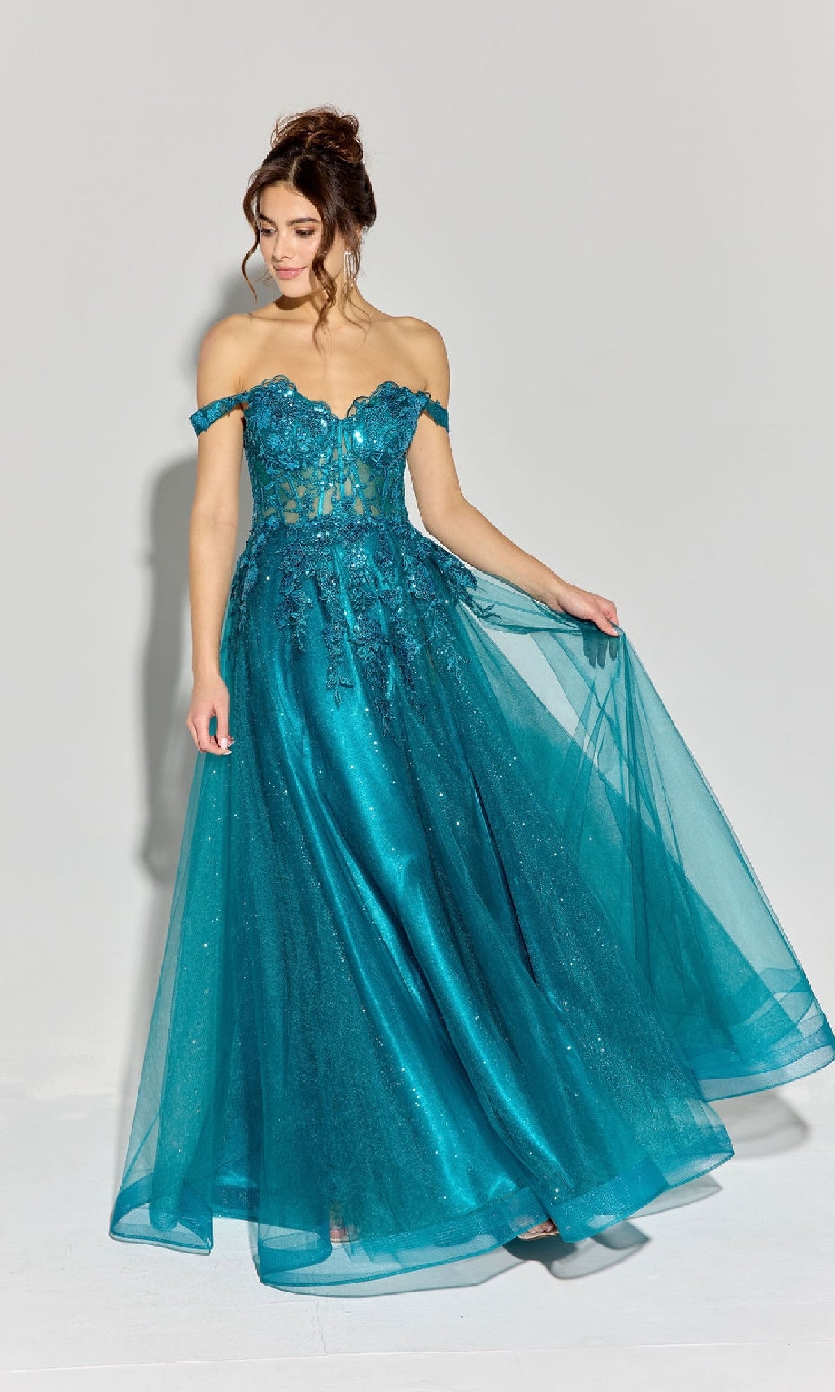 A woman wearing the Eureka EK128 Off-Shoulder Long Prom Ball Gown, featuring a teal sheer embroidered corset-style bodice and lace tulle skirt, stands against a plain light background.